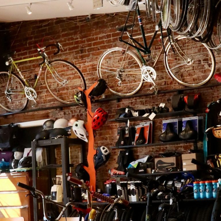 Fahrradgeschäft mit verschiedenen Bikes, Helmen und Zubehör an Wänden und Regalen.