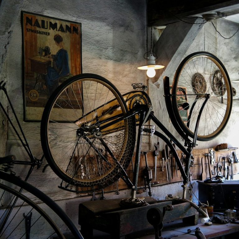 Ein Fahrrad an der Wand eines historischen Werkstattraums mit Werkzeugen.